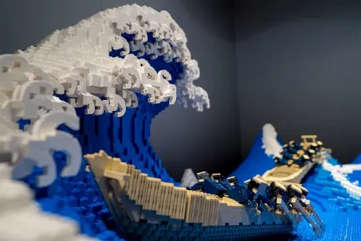 A large LEGO build of a great wave with a boat riding it